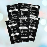 Multiple packets of b Condoms Supreme Black Condoms are arranged diagonally, displaying the brand name "bCondoms" along with the phrase "SUPPORT BLACK BUSINESSES." Made from ultra-smooth latex, these condoms provide a premium experience. The background features softly focused white and peach circles set against a light blue backdrop.
